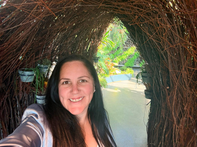 Laura Cowell smiling under a woven archway